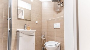 A modern bathroom with a glass shower enclosure, a white sink, and a toilet.