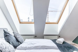 A bedroom with a skylight, a bed with pillows, and a radiator.