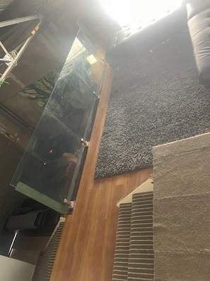 A modern interior with a glass elevator shaft, a textured wall, and a wooden floor.