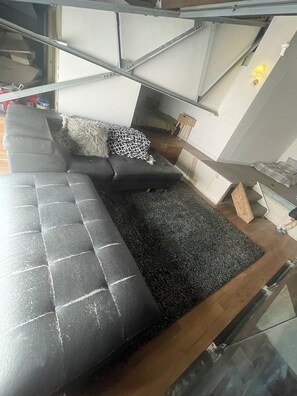 Een moderne woonkamer met een hoekbank, een bijzettafeltje en een lamp.