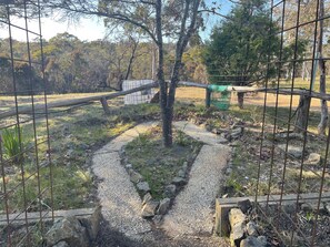 Un sendero de grava que lleva a una zona vallada con árboles y un edificio al fondo.