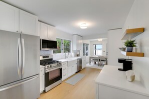 A modern kitchen with white cabinetry, a built-in oven, and a stainless steel refrigerator.