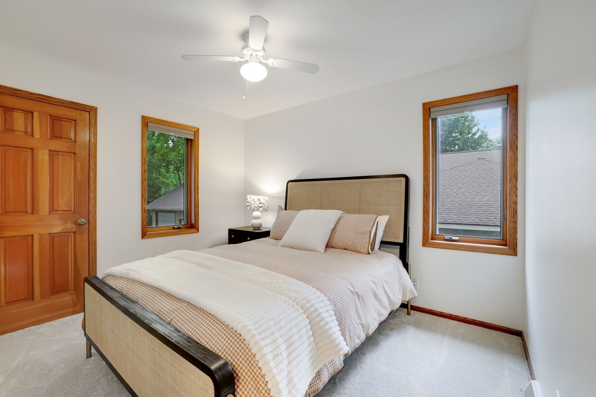A bedroom with a bed, a nightstand, a lamp, and a ceiling fan.