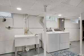 Une buanderie équipée d’un lave-linge, d’un évier et d’une fenêtre.