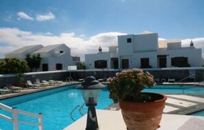 A swimming pool with lounge chairs, a lamp post, and a potted plant. - Your Winter Home by the Sea with a Pool (Playa Honda)
