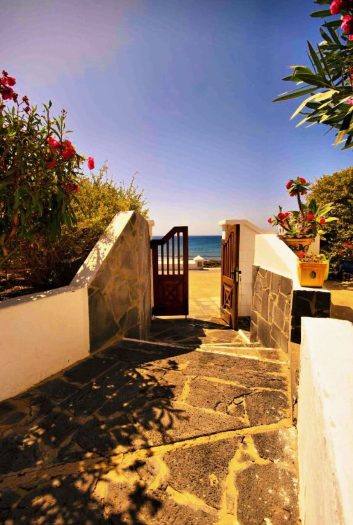 A stone staircase leading to a gate with a view of the sea in the background.