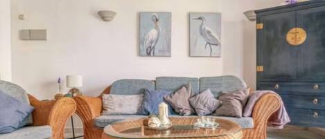A living room with a sofa, two armchairs, a coffee table, and wall art.