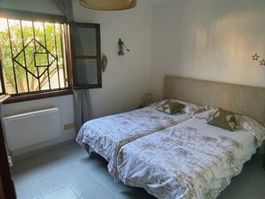 A bedroom with a bed, a window with a geometric pattern, a radiator, and a wall-mounted mirror. - Your Winter Home by the Sea with a Pool (Playa Honda)