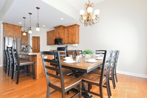 A modern kitchen with wooden cabinets, stainless steel appliances, and a dining area with a wooden table and chairs.