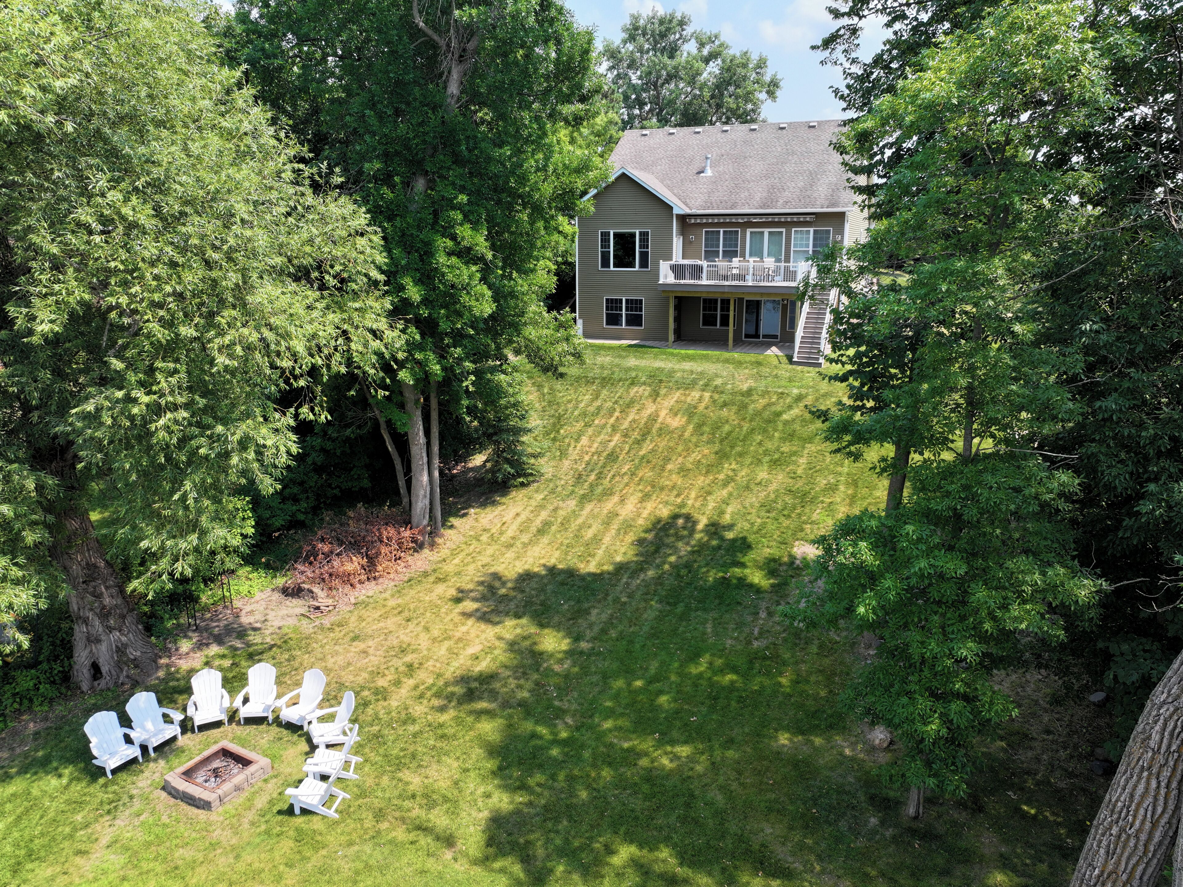 A residential property with a large lawn, a deck, and a fire pit area.