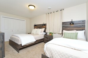 A bedroom with two beds, a wooden headboard, a nightstand, and a ceiling light fixture.