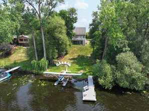 A lakeside property with a house, a dock, and a seaplane.