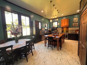 A kitchen with a marble floor, wooden cabinets, a central island, and a dining area with a table and chairs. - A little history. A lot of heart. Award Winning Historic Estate in the Delta. (Rolling Fork)