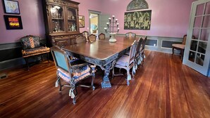 Una sala da pranzo con un grande tavolo di legno, sedie decorate e un lampadario.