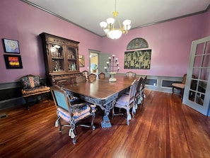 A dining room with a large wooden table, ornate chairs, and a chandelier.