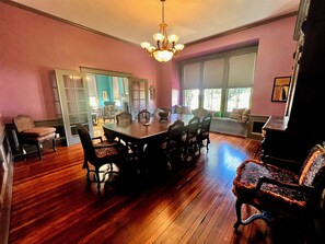 A dining area with a wooden table and chairs, a chandelier, and a view through a window. - A little history. A lot of heart. Award Winning Historic Estate in the Delta. (Rolling Fork)