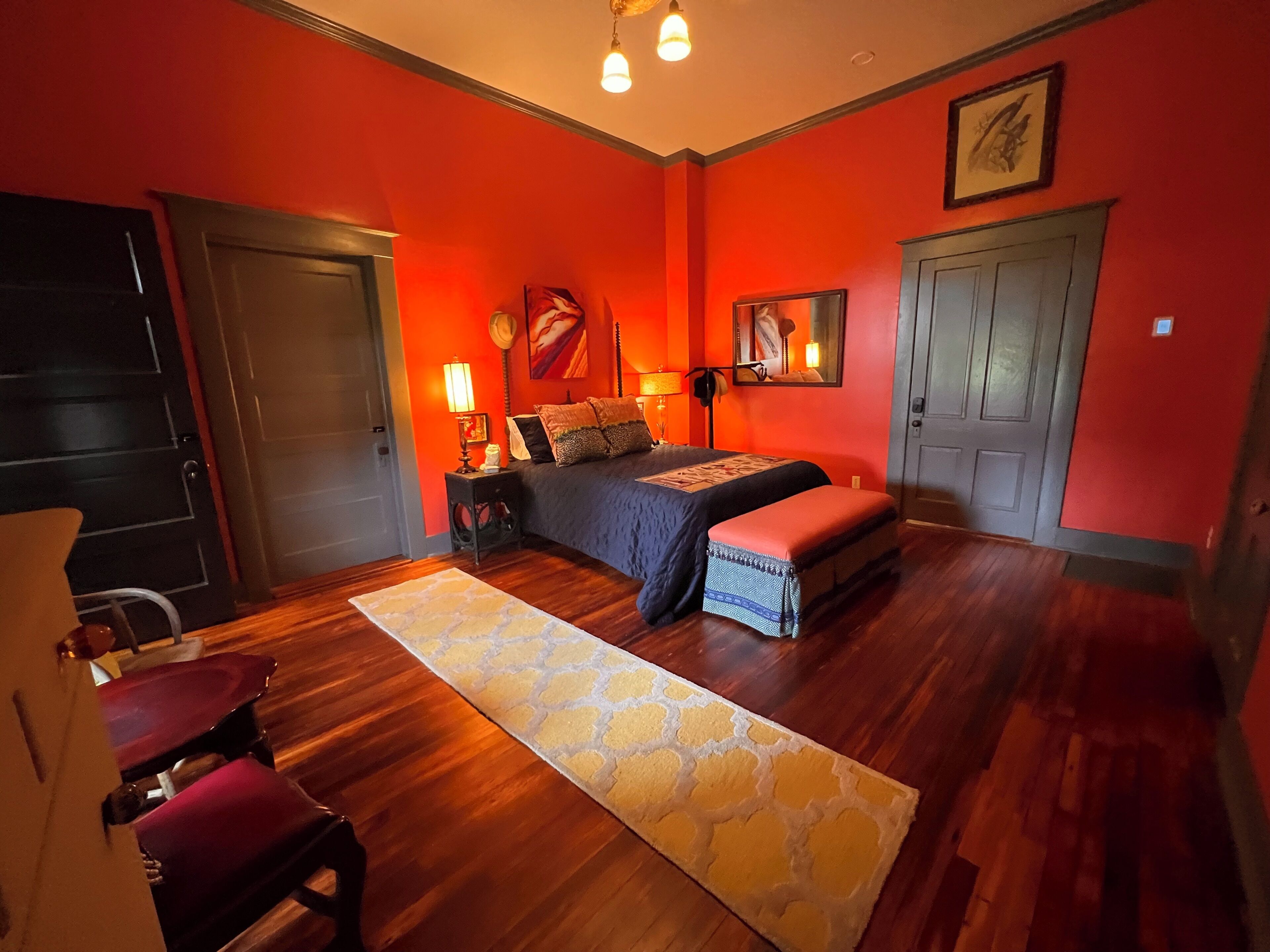 A room with a bed, a nightstand, a lamp, a chair, and a door.