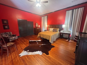 A room with a bed, a chair, a nightstand, and a cowhide rug.