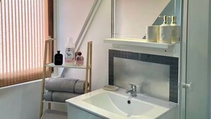 Un baño moderno con un lavamanos blanco, un espejo encima y un perchero para toallas.