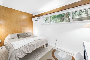 A bedroom with a bed, a window with blinds, an air conditioning unit, and a small desk. - Sunny Lido Beach Studio (Sarasota)