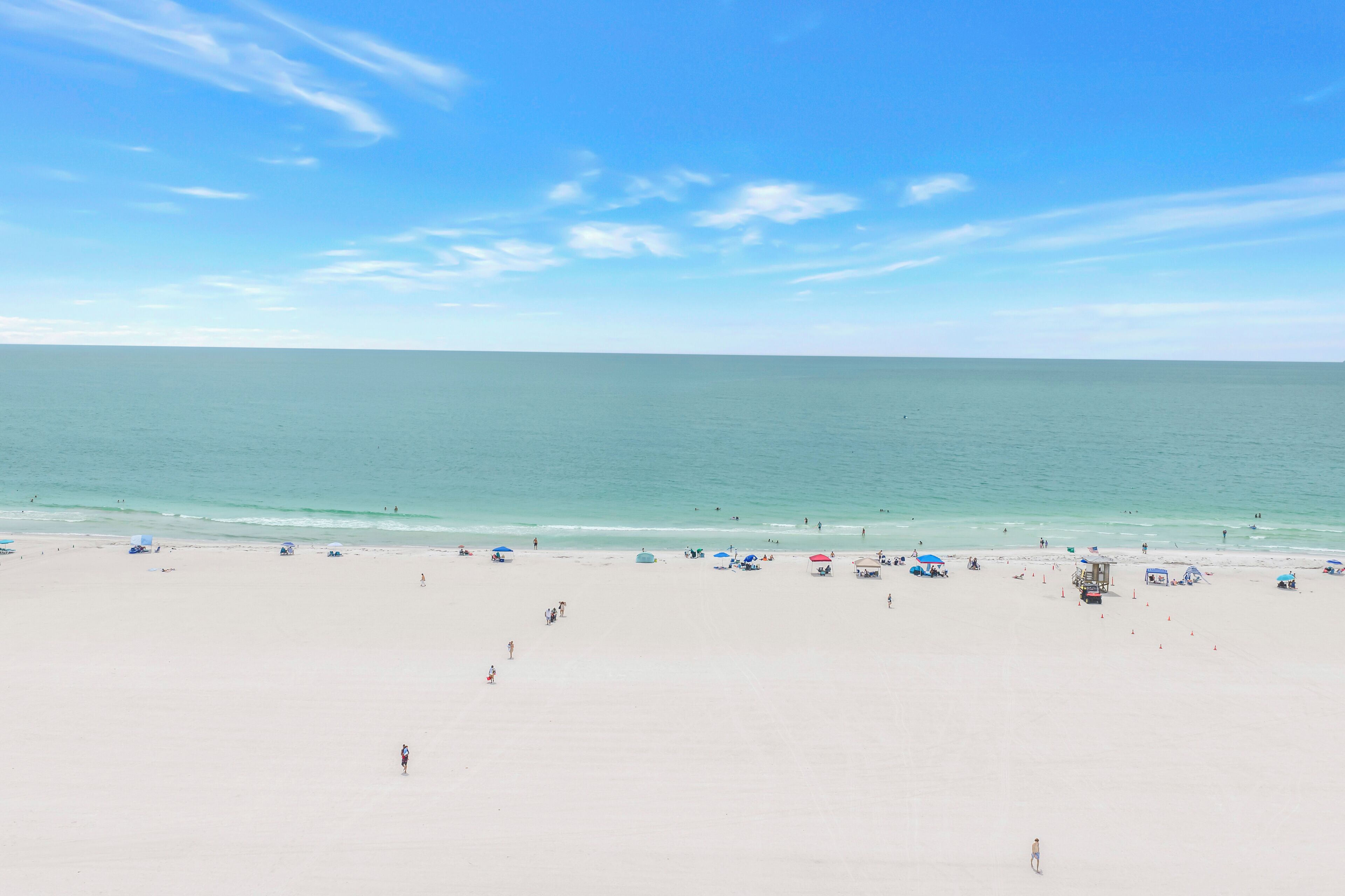 A wide sandy beach with a clear sky and calm sea.