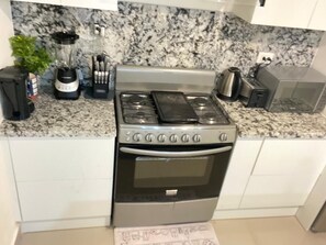 A kitchen with a gas stove, oven, and a granite countertop. - Spacious 3-bedroom 3-bathroom house in Gated Community Punta Cana DR (Punta Cana)
