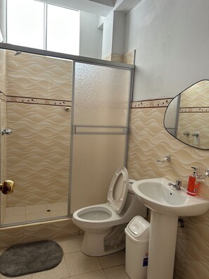 A bathroom with a toilet, sink, and shower.