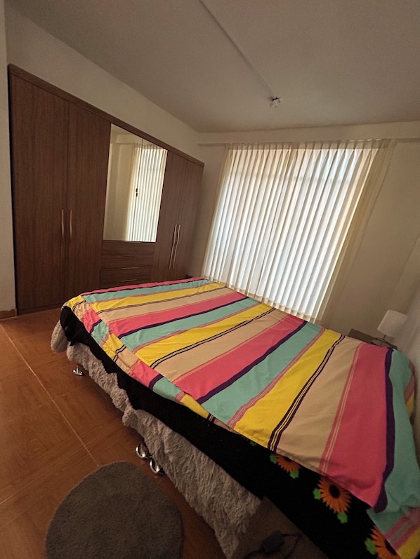 Un dormitorio con cama, armario y ventana con persianas.