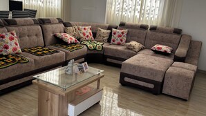 Una sala moderna con un sofá modular, una mesa de centro de vidrio y un televisor de pantalla plana.