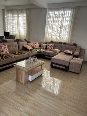 A modern living room with a sectional sofa, a glass coffee table, and a flat-screen TV.