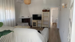 Una habitación con una cama, un televisor sobre un soporte de madera, una chimenea y una estantería.