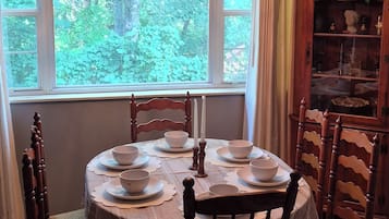 Una sala da pranzo con un tavolo rotondo apparecchiato per quattro persone, circondato da sedie in legno.