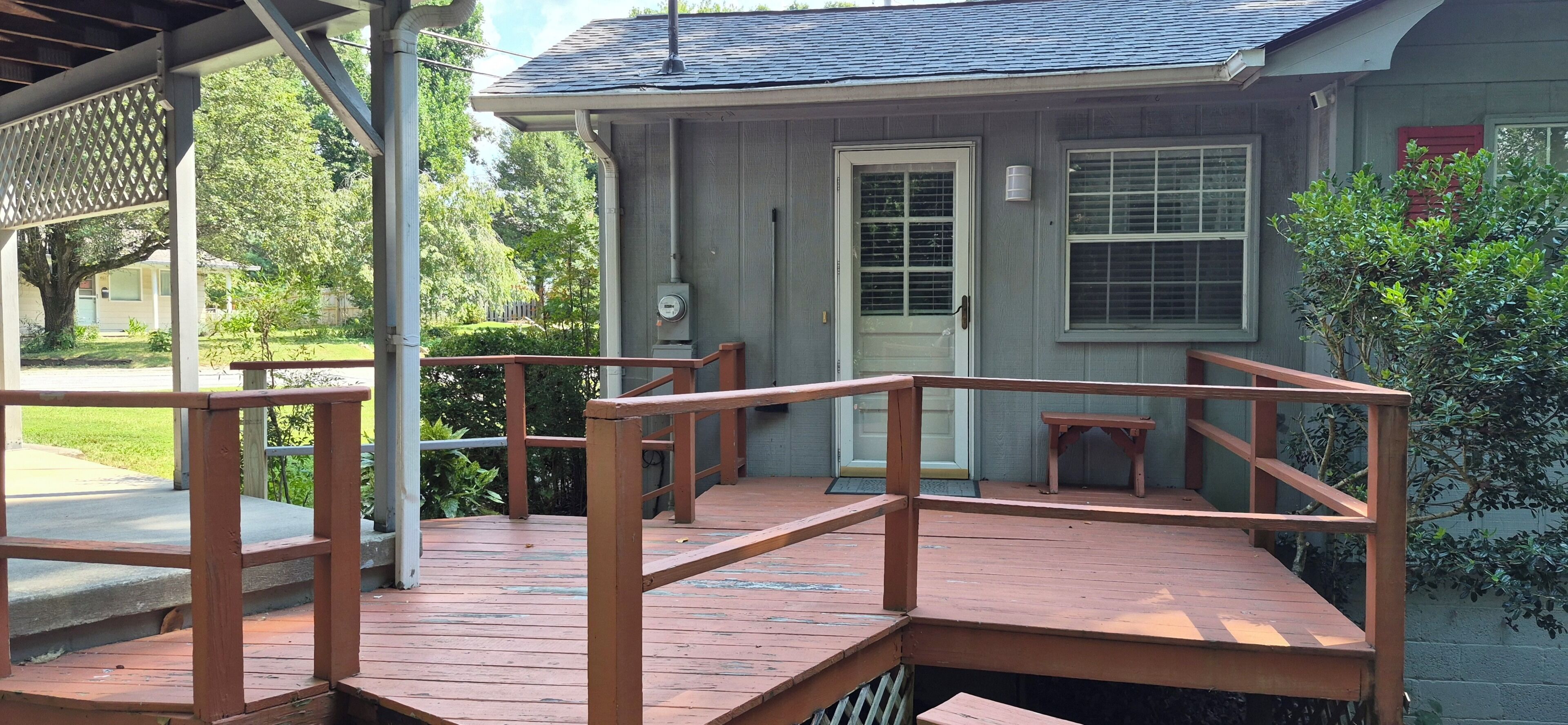 A wooden deck with a railing, a front door, and a window.