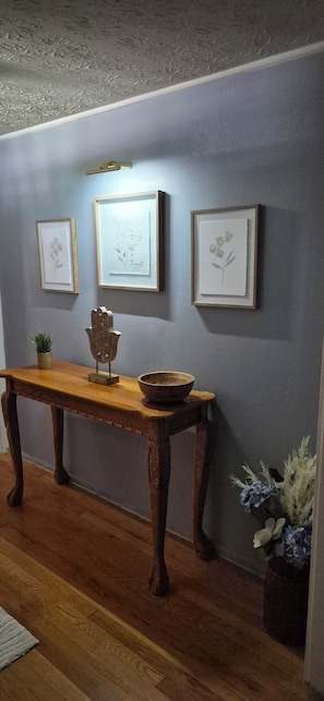 A room with a wooden console table, a wall-mounted light fixture, and framed artwork. - Greenbelt Getaway 3 Bedroom Home in Oak Ridge TN (Oak Ridge)