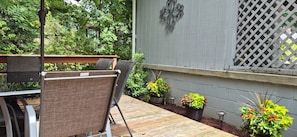 An outdoor patio with a wooden deck, metal chairs, and potted plants. - Greenbelt Getaway 3 Bedroom Home in Oak Ridge TN (Oak Ridge)