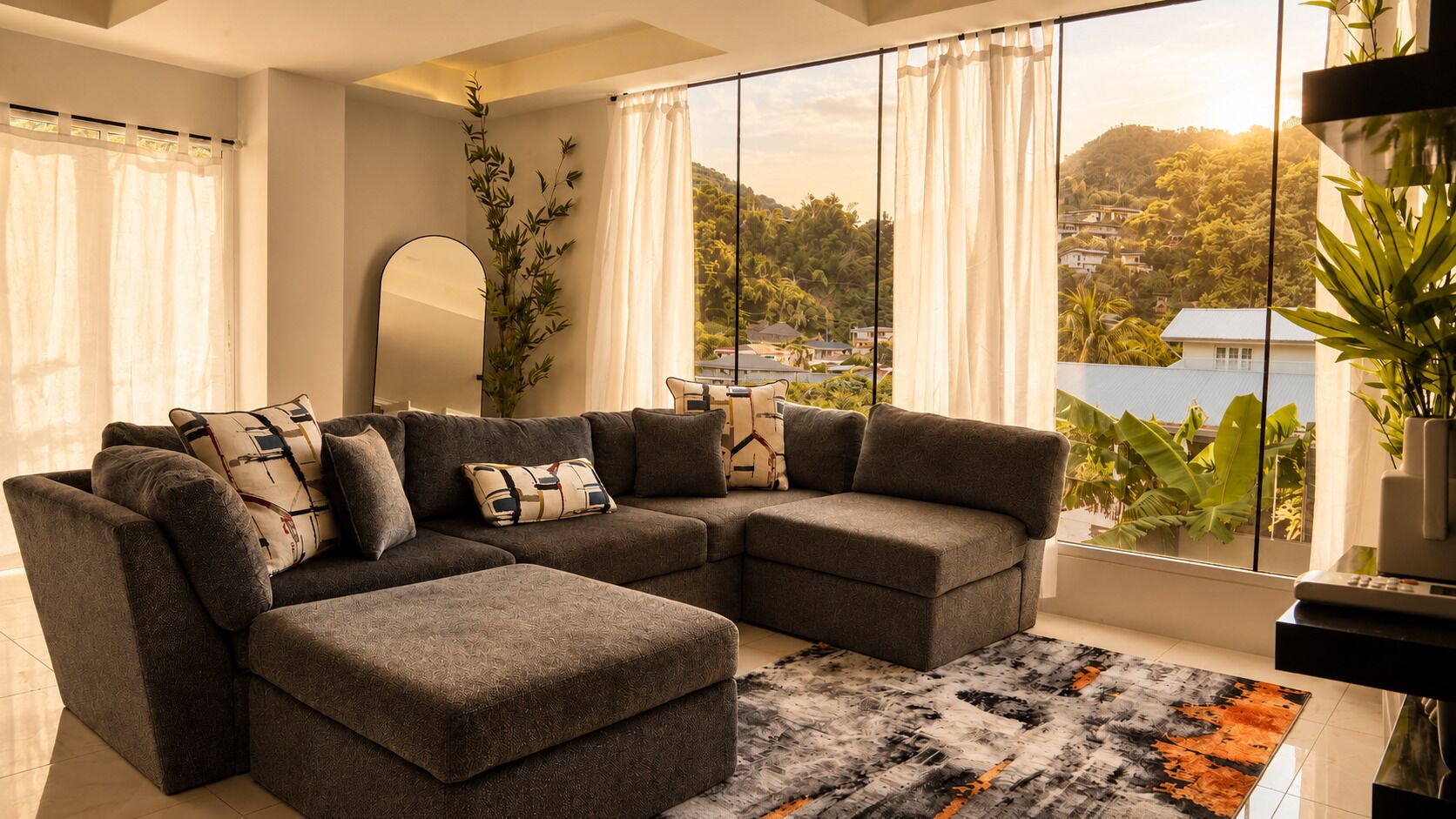 Ein modernes Wohnzimmer mit einem Ecksofa, einem großen Fenster mit Blick auf eine Hügelkette und einer Zierpflanze.