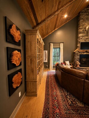 Una sala acogedora con chimenea de piedra, un sofá de cuero y una estantería de madera.