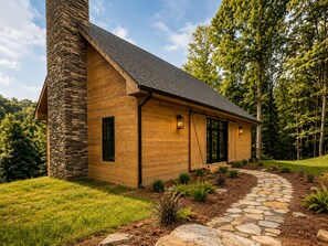 A modern log cabin with a stone chimney, a stone pathway, and a forested backdrop. - Luxury Private Mountain Spa - Trout Fishing + Trails (Copper Hill)