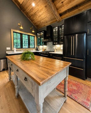 A kitchen with a large wooden island, black cabinets, and a rustic ceiling. - Luxury Private Mountain Spa - Trout Fishing + Trails (Copper Hill)