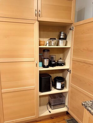 A kitchen with wooden cabinets, a blender, a coffee maker, and a rice cooker. - Cozy Canton Stay (Baltimore)