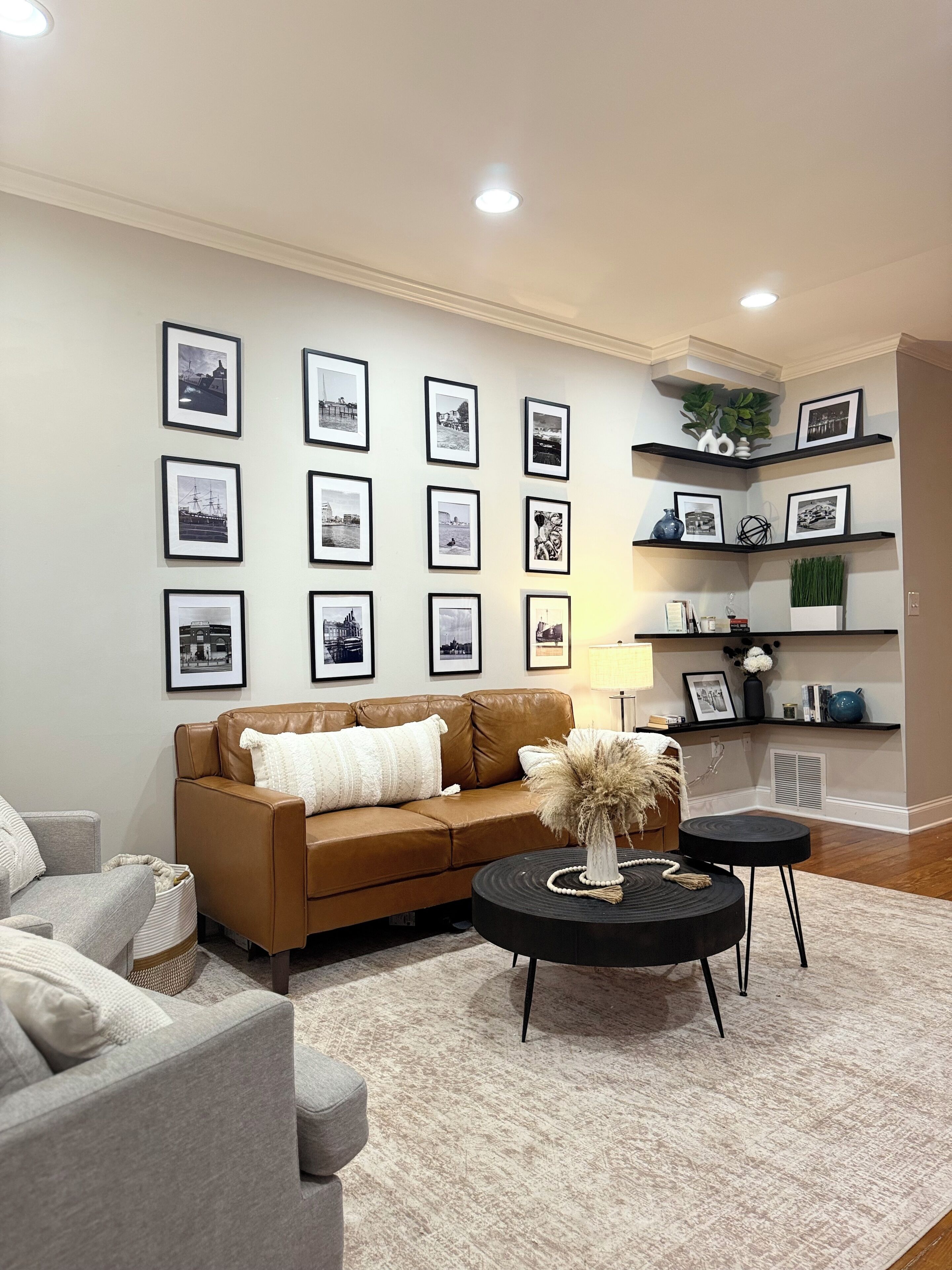 A living room with a brown sofa, a grey armchair, a black coffee table, and a patterned rug.