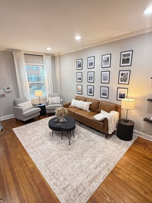 A living room with a sofa, armchairs, a coffee table, a rug, and framed pictures on the wall. - Cozy Canton Stay (Baltimore)