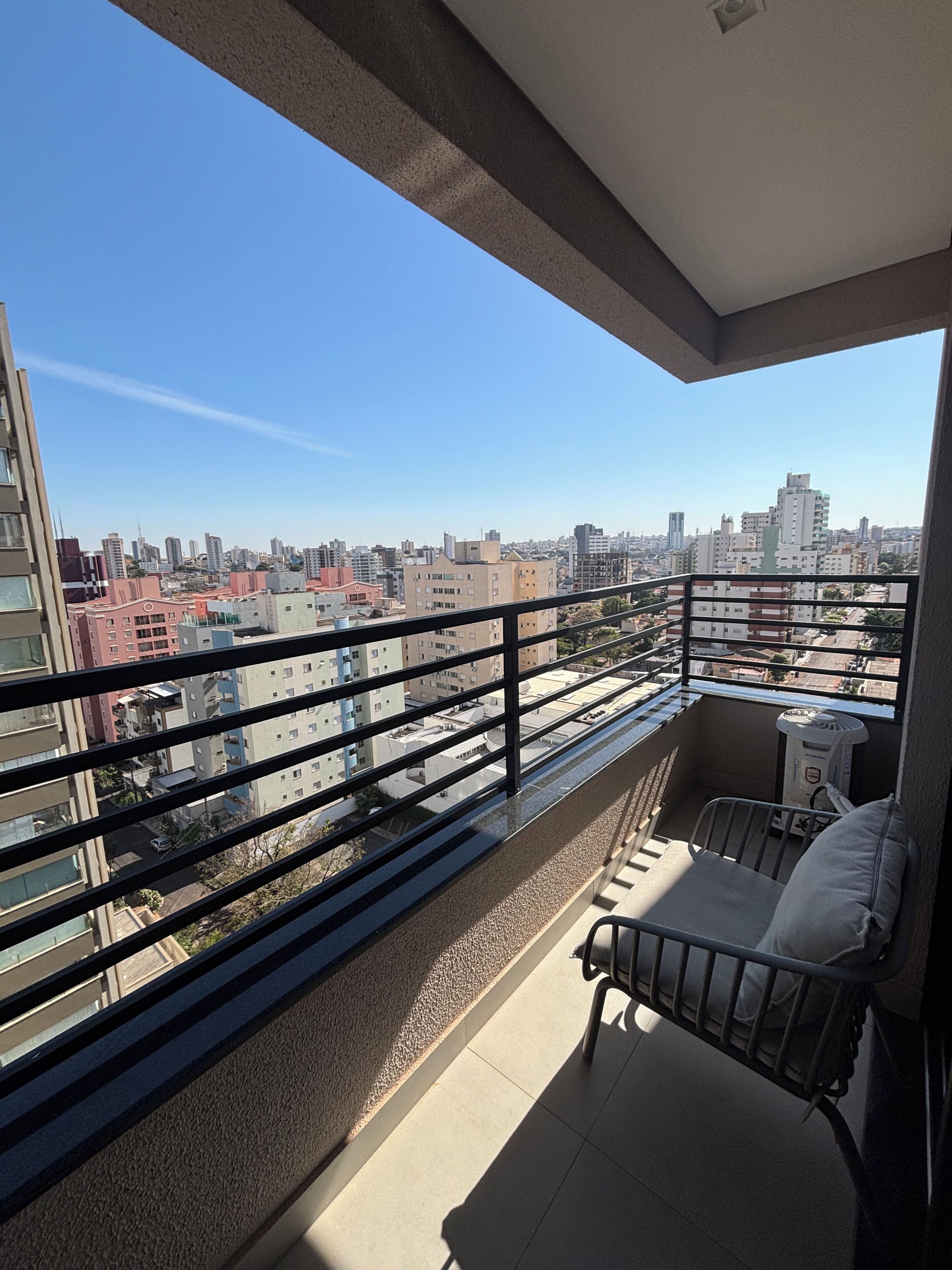 Ein Balkon mit Blick auf eine Stadtlandschaft, einem kleinen Tisch und einem Stuhl.