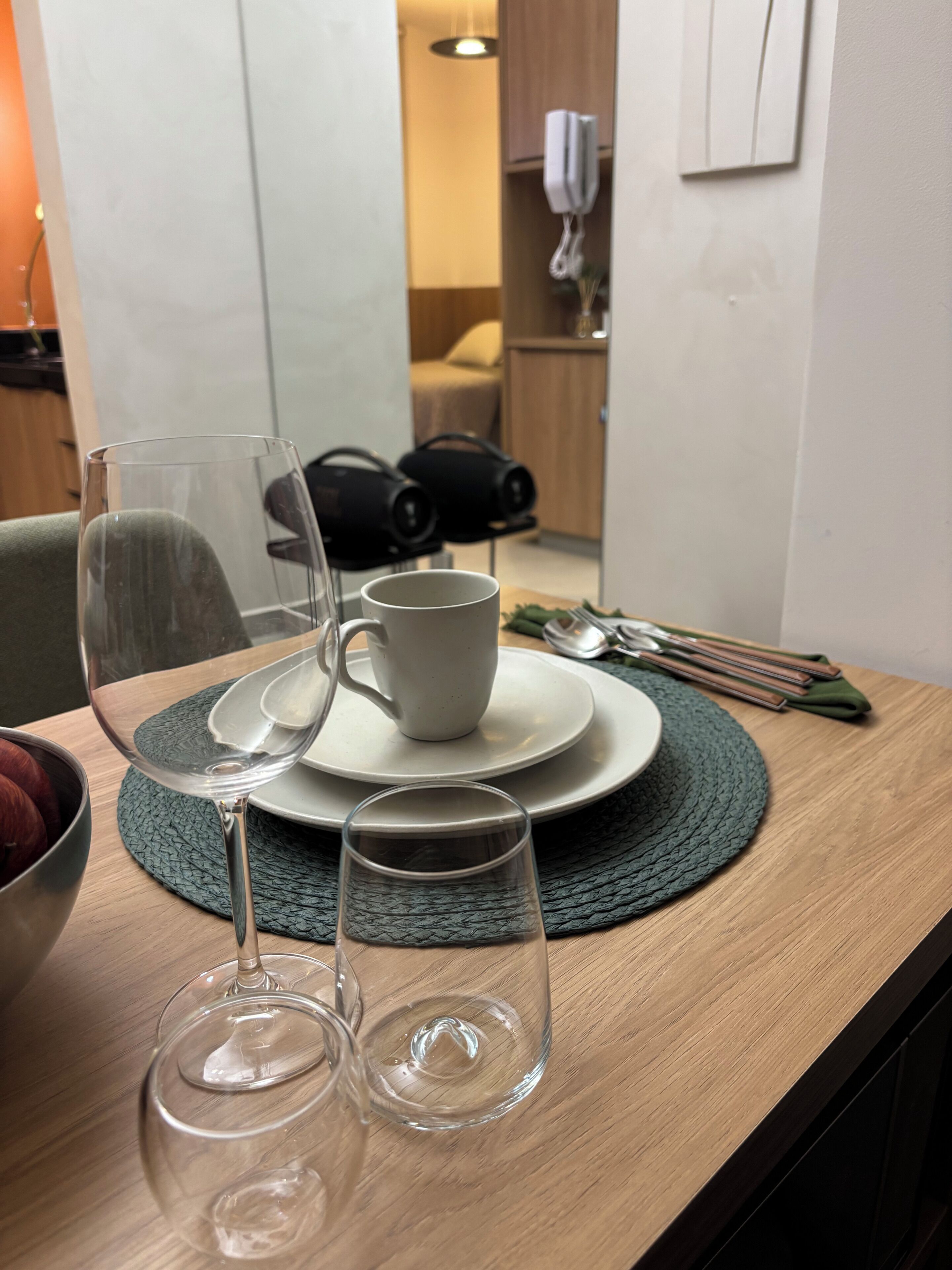Una mesa de comedor con un tazón, una taza y dos copas de vino.
