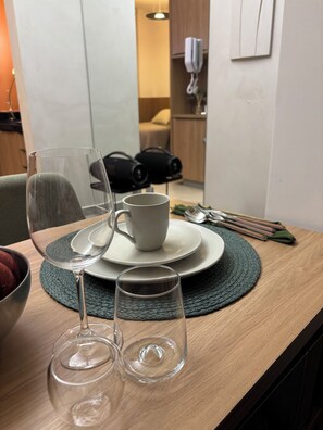 Una mesa de comedor con un tazón, una taza y dos copas de vino.