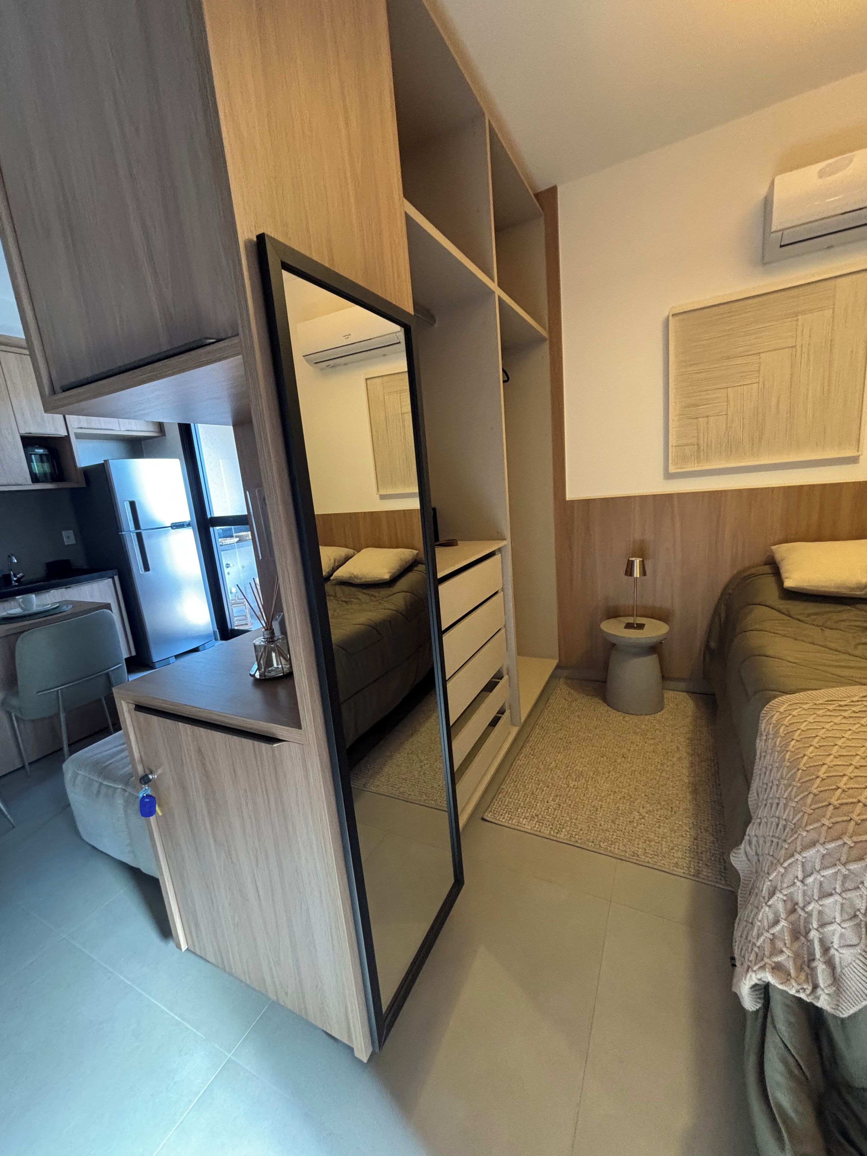 A compact bedroom with a bed, bedside table, and a wardrobe with a mirror.
