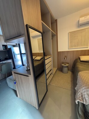 A compact bedroom with a bed, bedside table, and a wardrobe with a mirror. - Monte Olympus: Apt moderno com sacada 10º andar (Uberlândia)