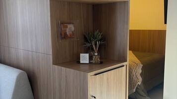 Una habitación moderna con un armario empotrado de madera, una planta pequeña y una cama con manta.