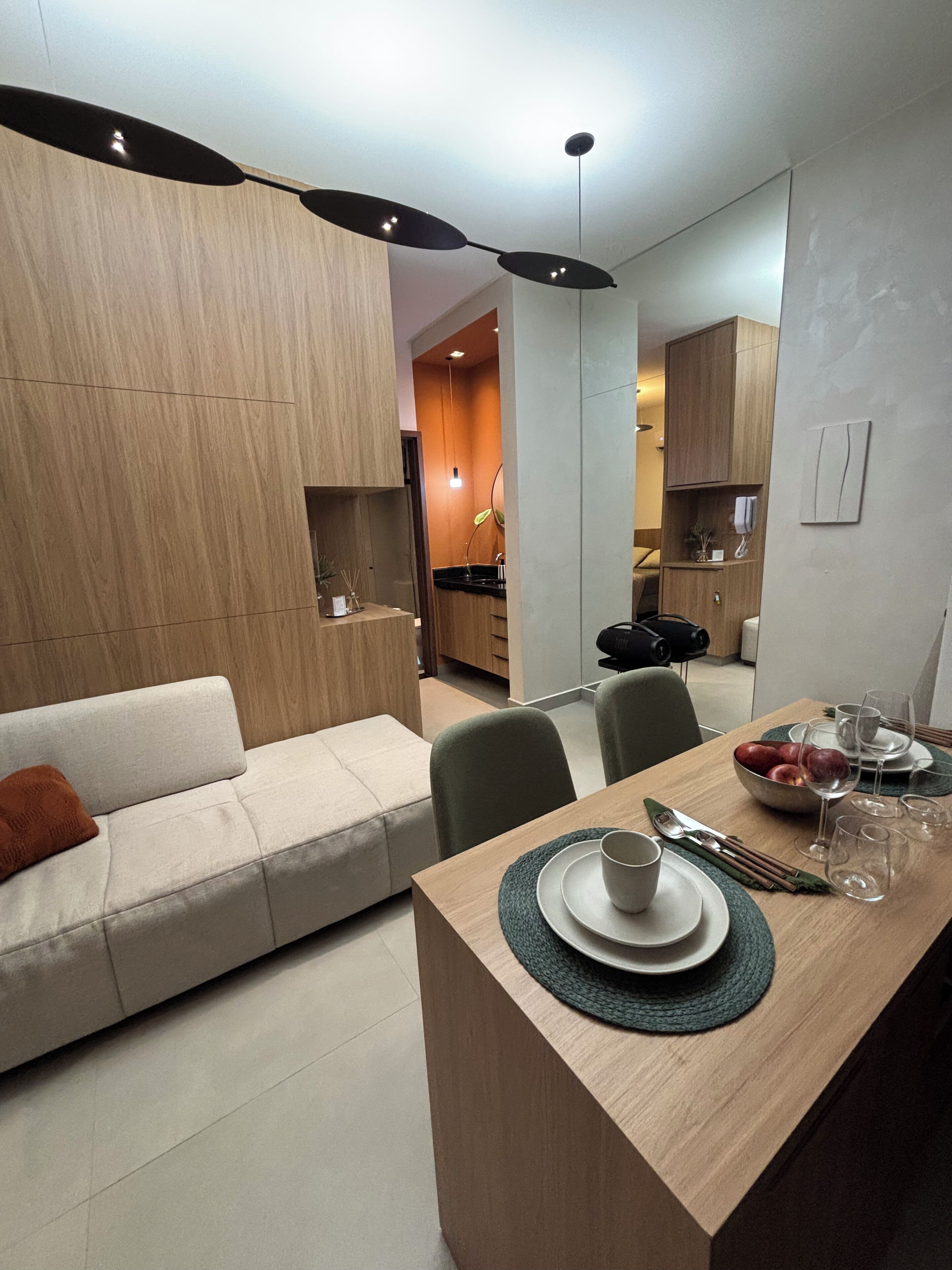 A modern living room with a sofa, dining table set with plates, glasses, and cutlery.