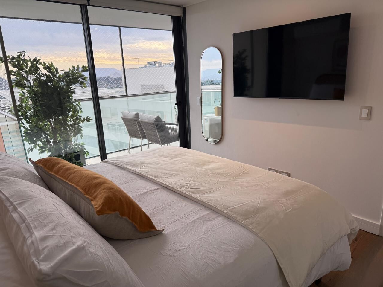 Un dormitorio con cama, televisor y vista a la ciudad.